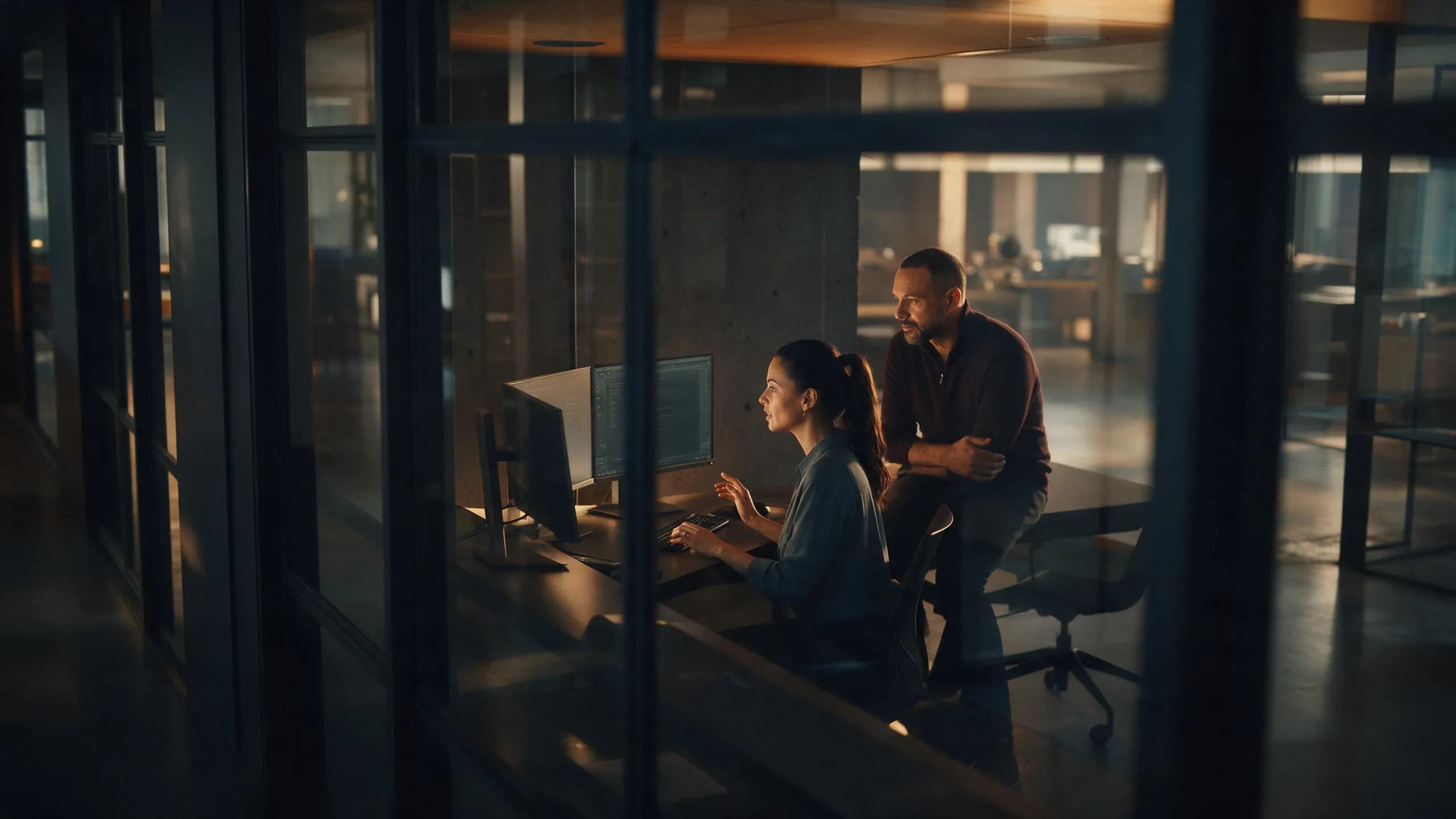 Two colleagues reviewing data on a desktop monitor