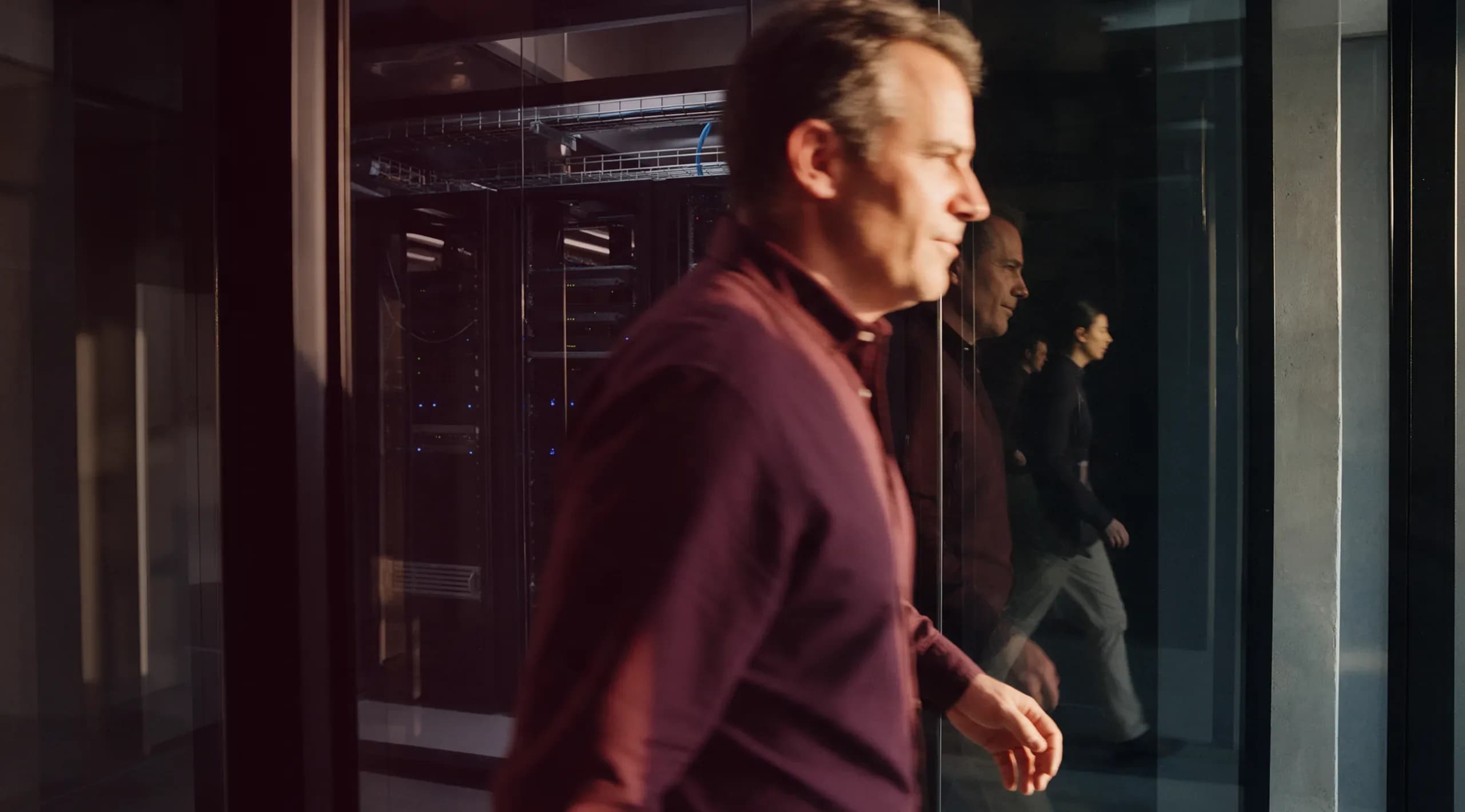 A colleague walking past a glass-walled server room